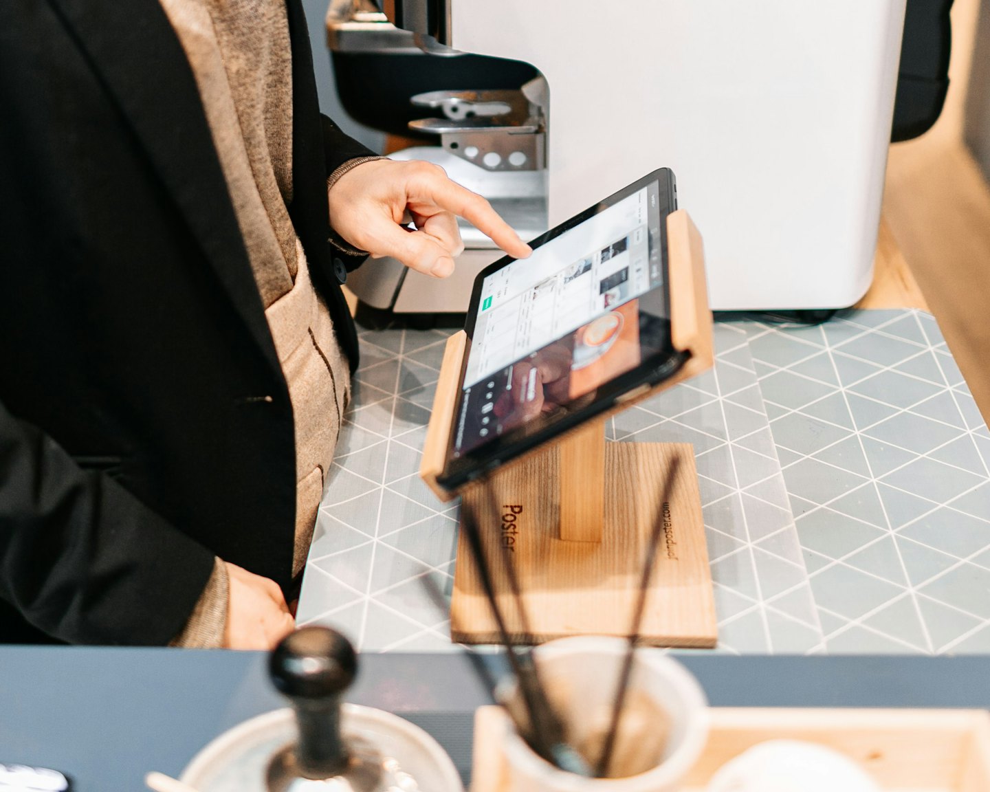 Mano usando una tableta digital en un mostrador de negocios.